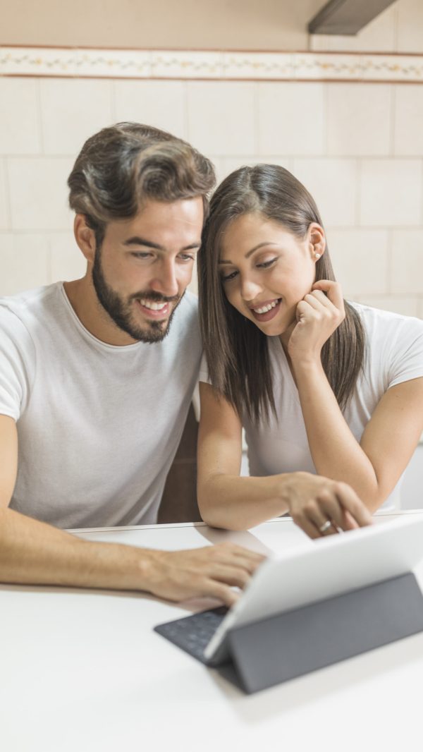 sonriente-pareja-viendo-la-tableta-en-la-mesa